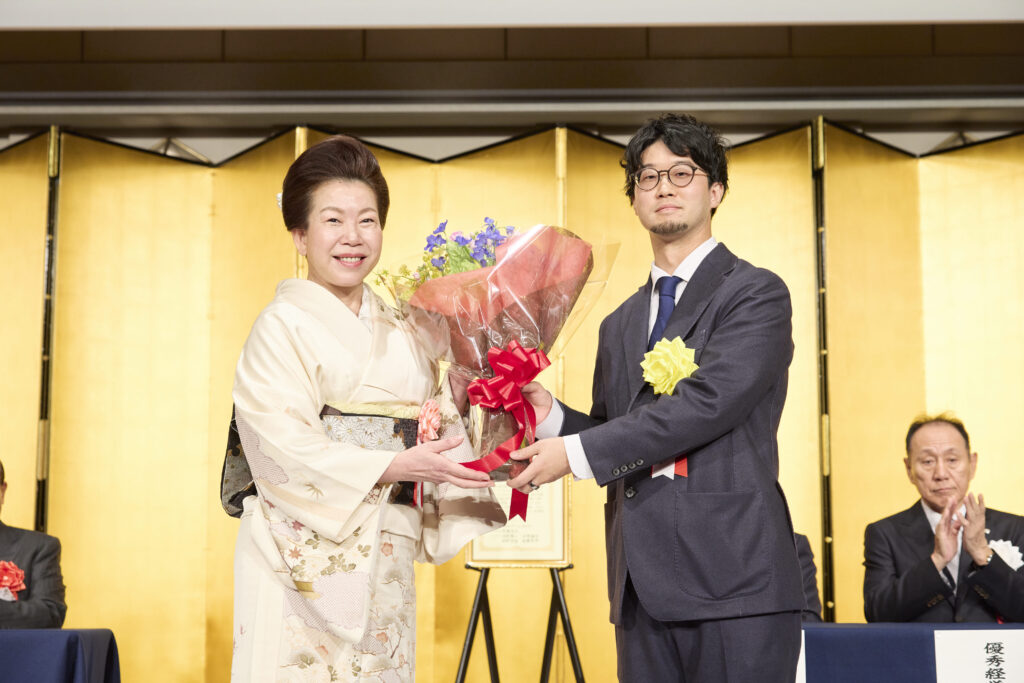 弊社社長の佐藤有美から花束を受け取る藪氏
