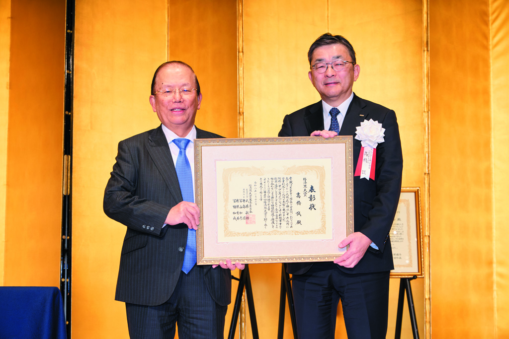 審査委員長の武藤敏郎・大和総研名誉理事（左）から表彰状を受け取る高橋誠・KDDI会長