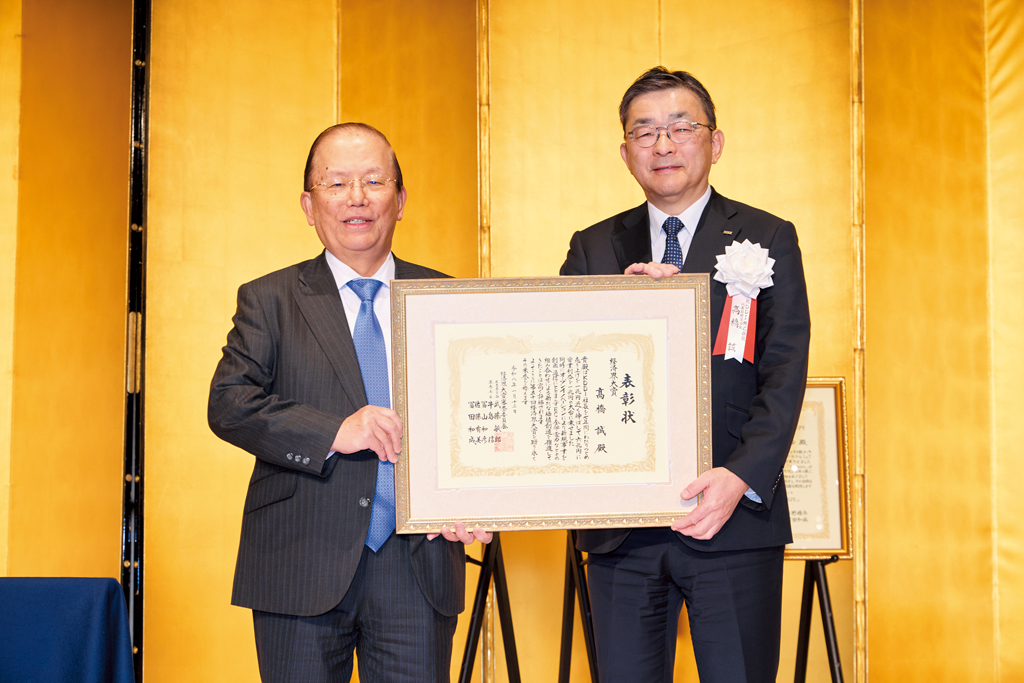 審査委員長の武藤敏郎・大和総研名誉理事（左）から表彰状を受け取る高橋誠・KDDI会長